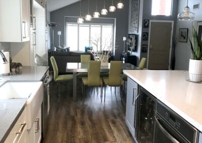 A kitchen with white cabinets and hardwood floors.