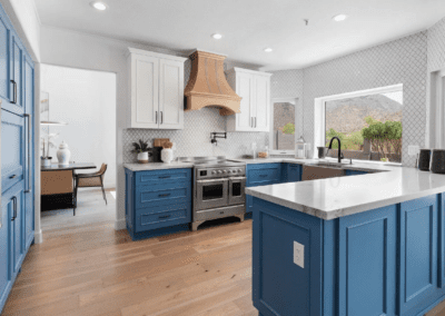 A kitchen with blue cabinets and white counter tops.