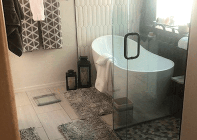 A bathroom with a glass shower door and a bathtub.